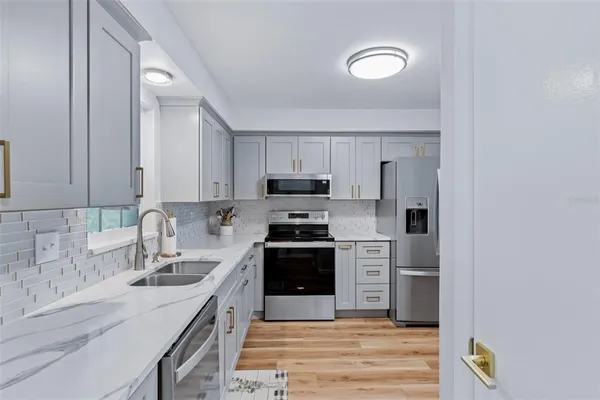 a kitchen with cabinets stainless steel appliances a sink and a stove