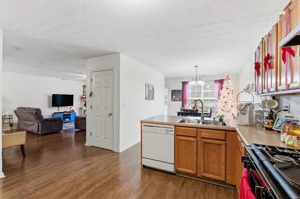 a kitchen with stainless steel appliances a stove top oven a sink a dining table and chairs with wooden floor