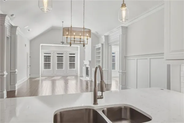 a view of a kitchen with a sink wooden cabinets and chandelier