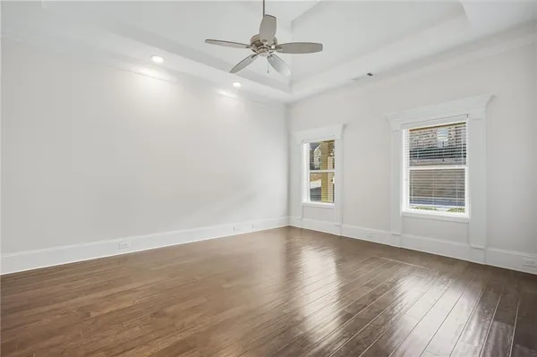 an empty room with wooden floor chandelier fan and windows