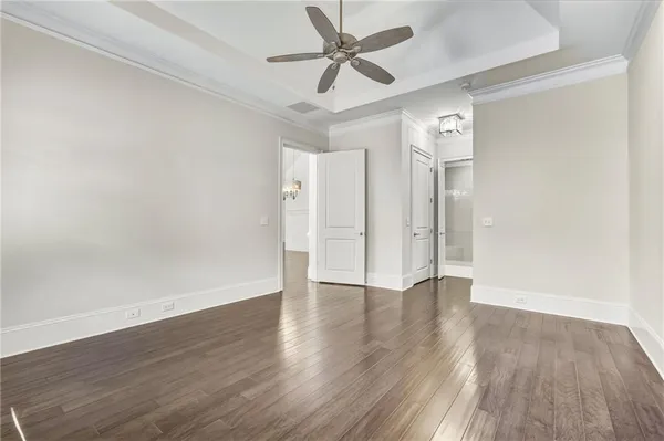 an empty room with wooden floor and ceiling fan