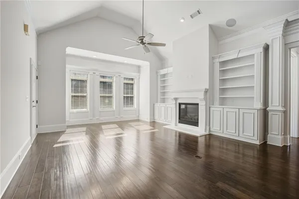 a view of an empty room with wooden floor fireplace and a window