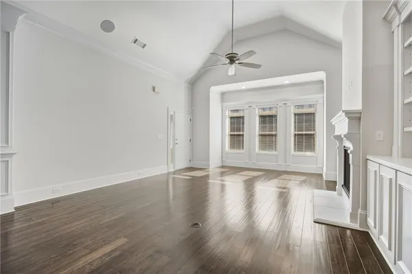 a view of an empty room with wooden floor and fan
