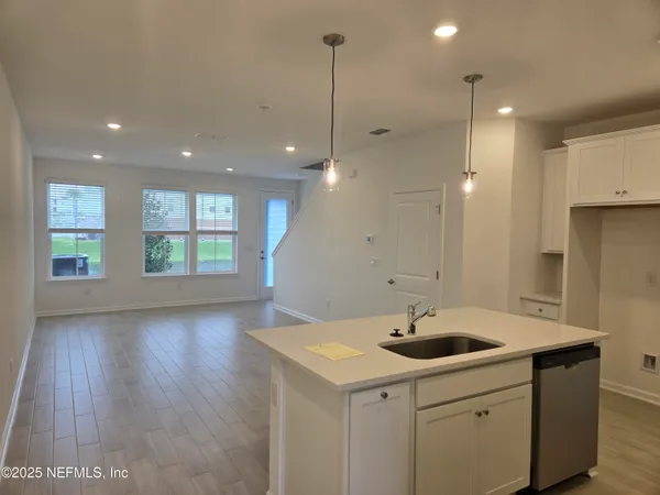 a kitchen with stainless steel appliances granite countertop a sink a window and wooden floor