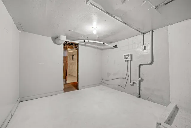 an empty room with chandelier fan and windows