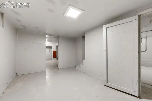 an empty room with chandelier fan and windows