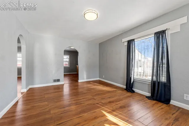 a view of empty room with wooden floor and fan