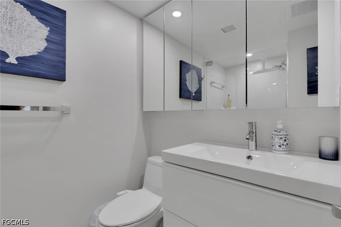 9 High Point Circle North, Unit 101 Naples, FL 34103 - Photo 31 of 49 a bathroom with a toilet sink and mirror