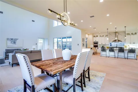 a dining room with wooden floor a chandelier a wooden table and chairs