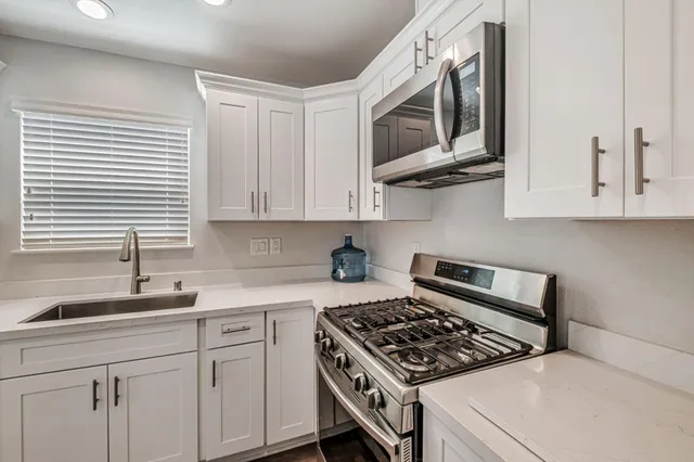 a kitchen with stainless steel appliances white cabinets and a stove top oven