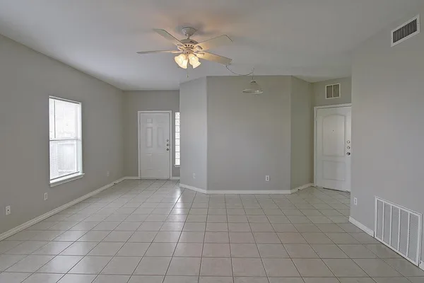 an empty room with fan and windows