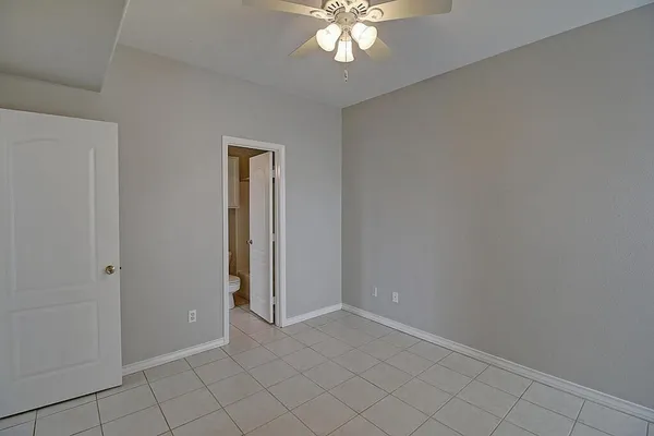 a view of an empty room with chandelier fan