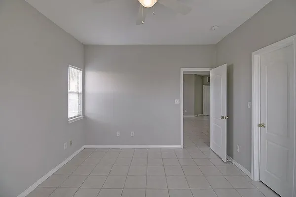 an empty room with a chandelier fan and windows