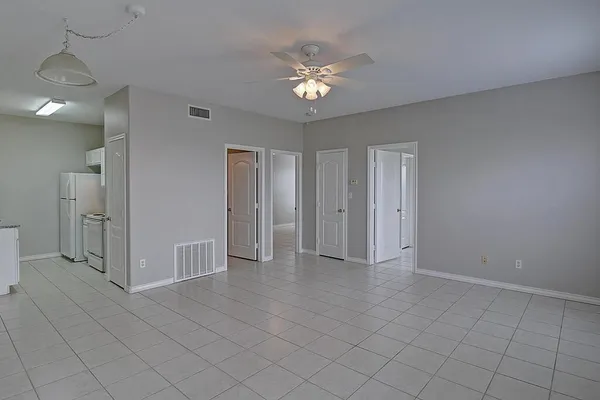 a view of an empty room with a chandelier fan