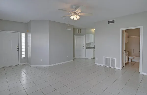 a view of an empty room and a kitchen