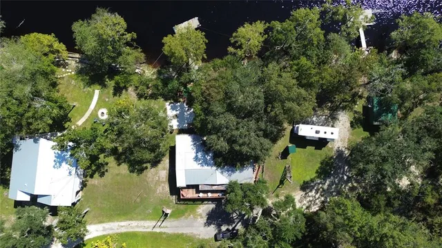 an aerial view of residential house with outdoor space and trees all around