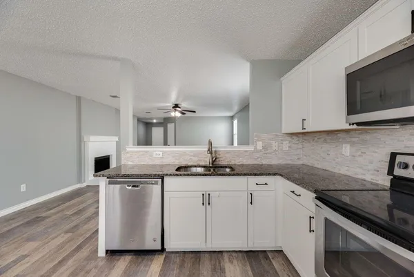 a kitchen with granite countertop a sink and a stove top oven