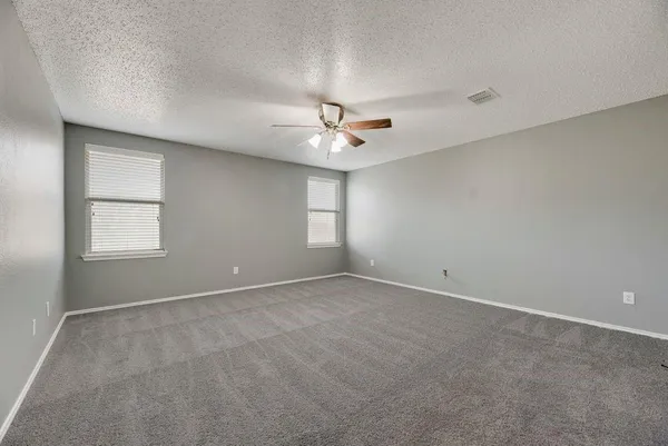 an empty room with windows and ceiling fan