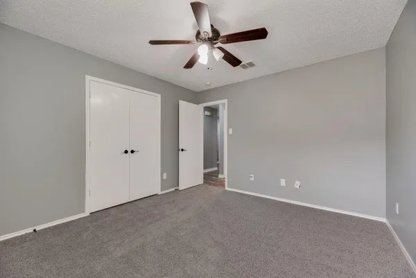 a view of an empty room and chandelier fan