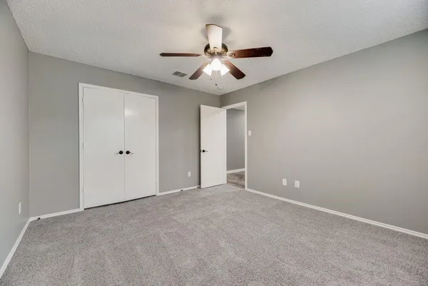 a view of an empty room and chandelier fan