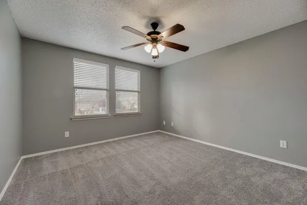 an empty room with window and ceiling fan