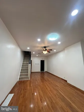 an empty room with wooden floor and staircase