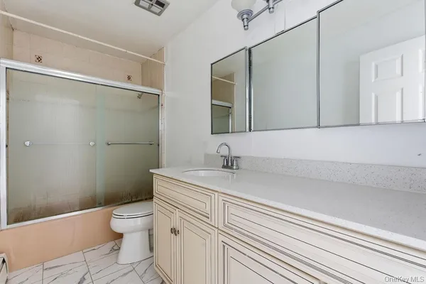 a bathroom with a granite countertop sink a toilet and a shower