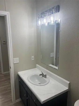 an empty room with wooden floor chandelier fan and windows