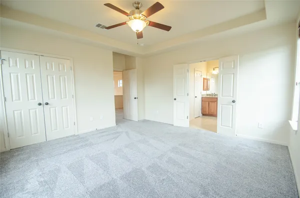 an empty room with closet and a ceiling fan
