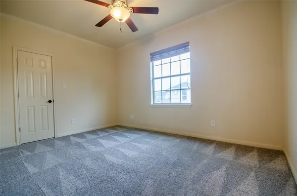 an empty room with a chandelier fan and windows