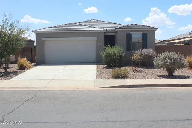 a front view of a house with garage and plants