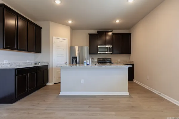 a large kitchen with kitchen island granite countertop wooden cabinets a stove a sink and dishwasher