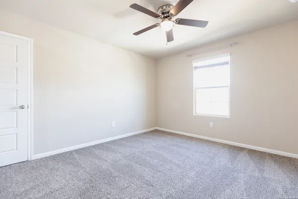 an empty room with a window and a fan