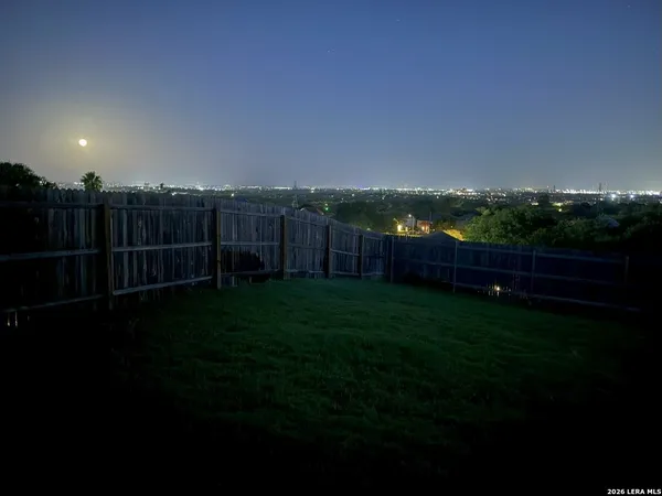 a view of a backyard with grass & fence