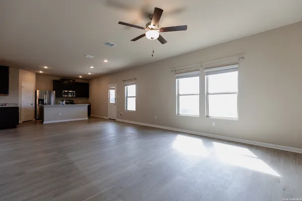 a view of an empty room with a kitchen and a window