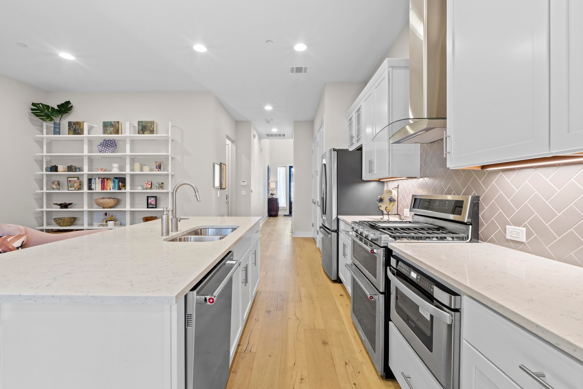4323 Spicewood Springs Road, Unit 6 Austin, TX 78759 - Photo 15 of 40 Kitchen featuring light stone counters, appliances with stainless steel finishes, white cabinets, light wood-style floors, and wall chimney range hood
