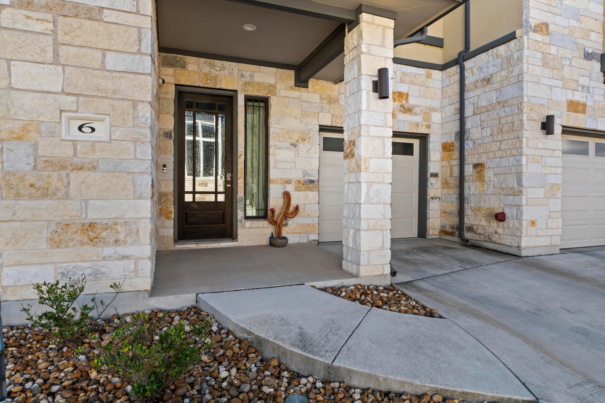 4323 Spicewood Springs Road, Unit 6 Austin, TX 78759 - Photo 2 of 40 View of exterior entry featuring covered porch, stone siding, and a garage