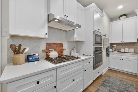 a kitchen with white cabinets and appliances
