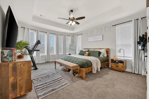a spacious bedroom with a bed and a flat screen tv
