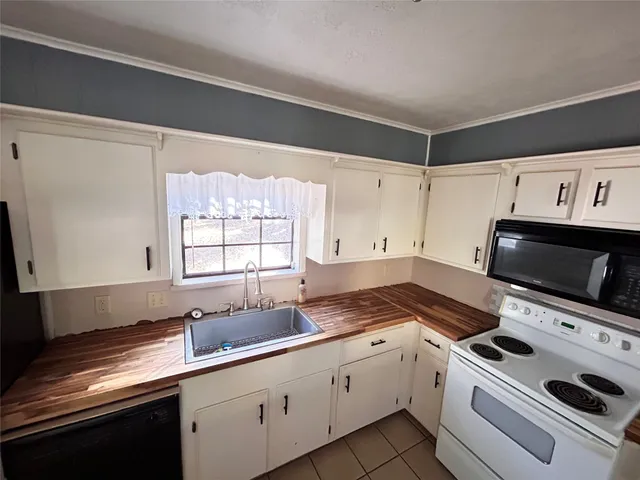 a view of a backyard with large trees and wooden fence