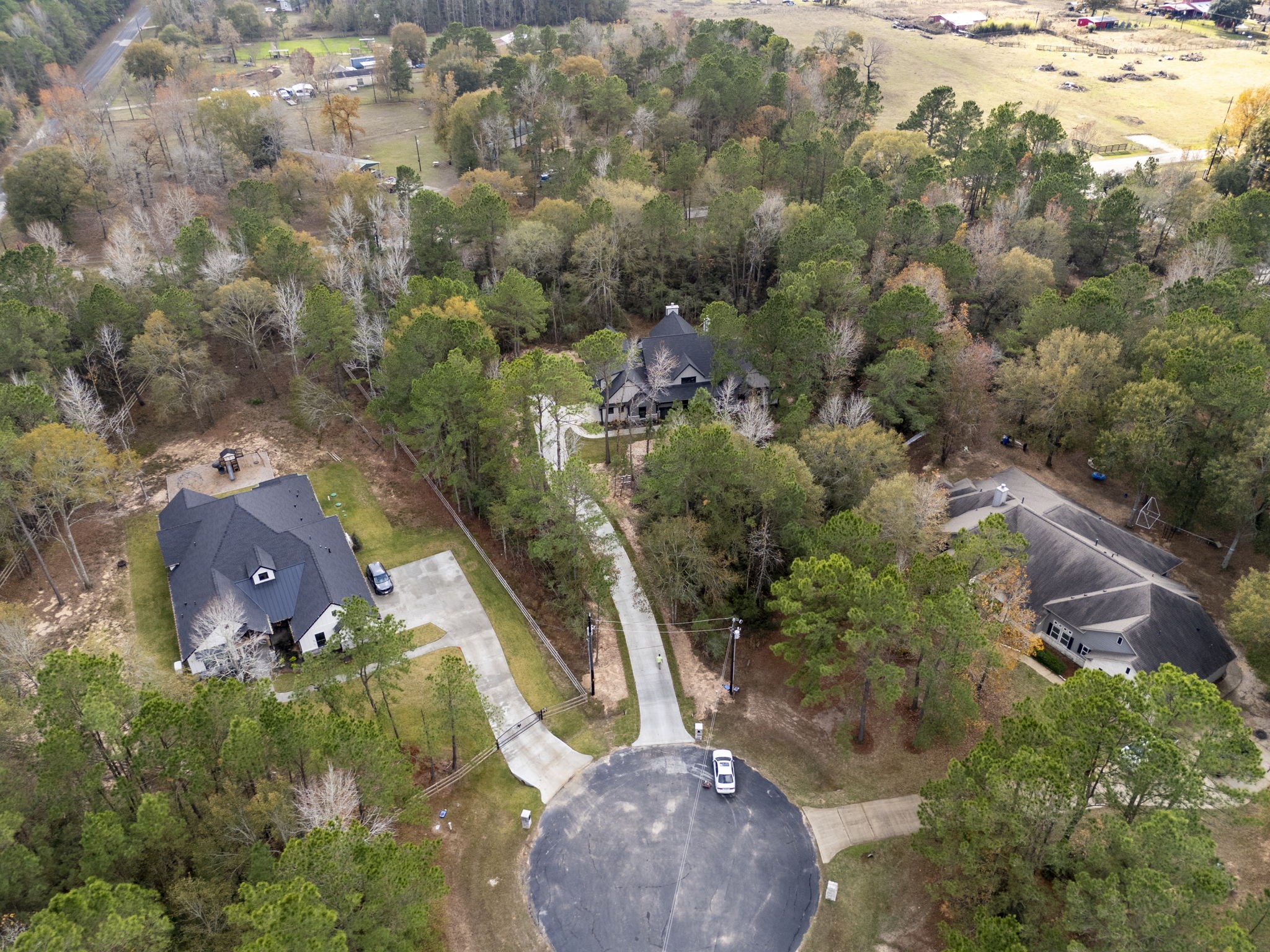 29001 Colin Court Waller, TX 77484 - Photo 2 of 47 This aerial photo showcases a cul-de-sac with several large homes nestled among dense trees, providing a secluded, natural setting. The properties are spacious, with long driveways and ample yards, offering privacy and a serene atmosphere.