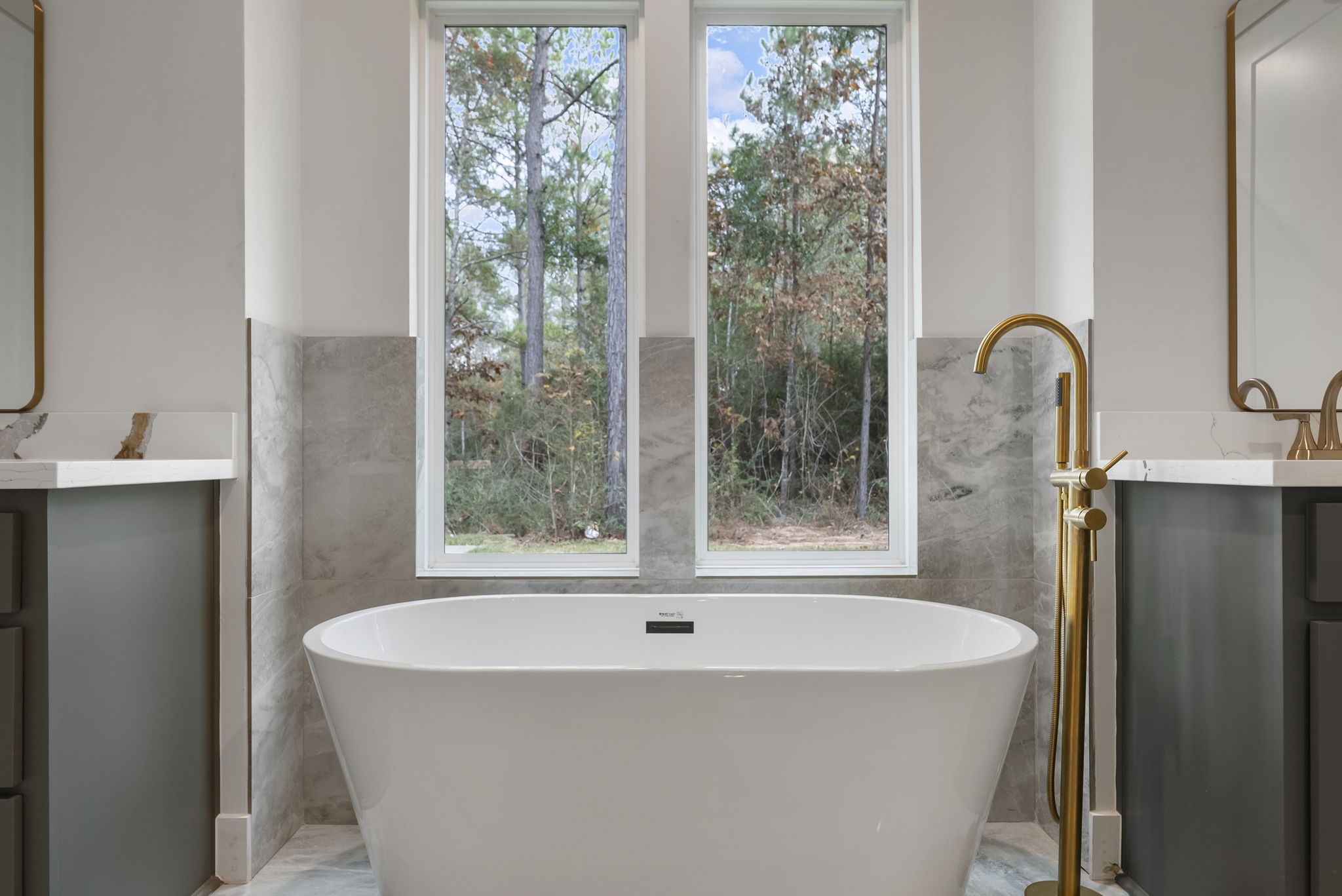 29001 Colin Court Waller, TX 77484 - Photo 24 of 47 The modern freestanding tub with a sleek gold faucet with windows that offer a view of the wooded outdoors, creating a serene atmosphere and privacy.