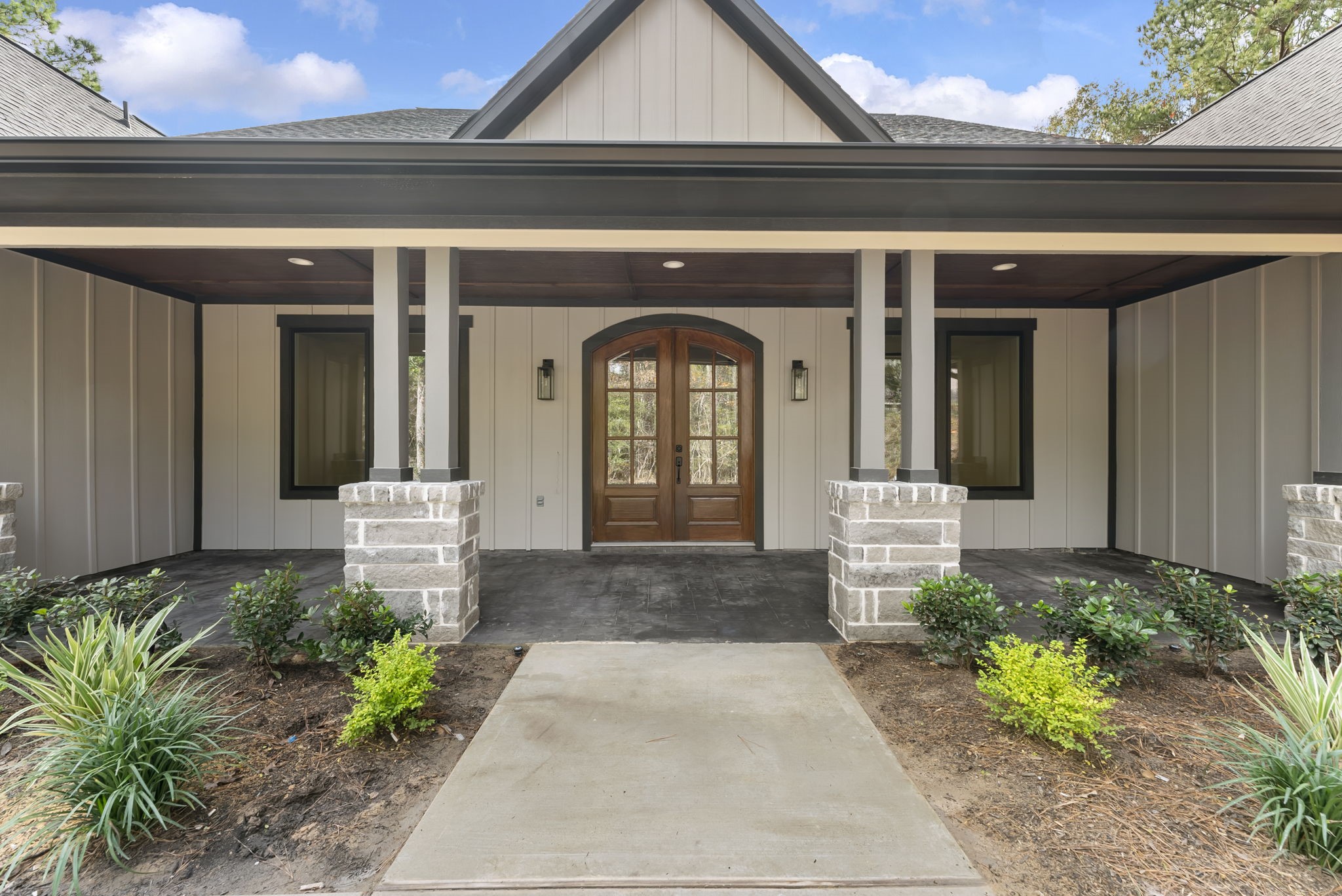 29001 Colin Court Waller, TX 77484 - Photo 4 of 47 Charming front entry with a covered porch, featuring a wood-paneled ceiling and elegant double doors. The exterior has modern paneling with brick accents, surrounded by landscaping.
