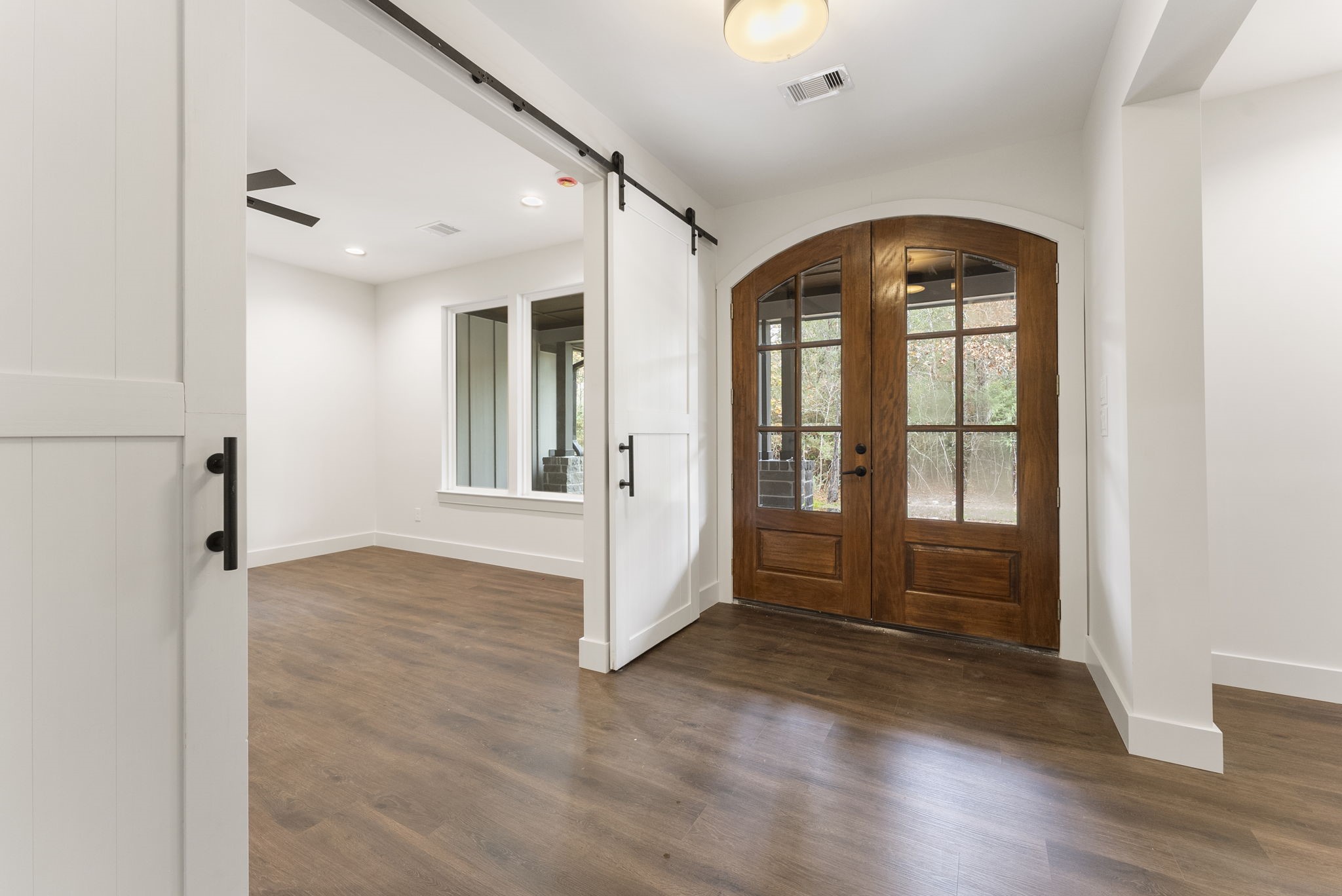 29001 Colin Court Waller, TX 77484 - Photo 7 of 47 This photo showcases a bright entryway with elegant double wooden doors and glass panels, leading to the study and dining room with plank floors and a large window, creating a welcoming space.