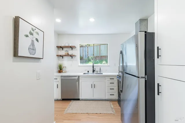 a kitchen with stainless steel appliances a refrigerator sink and white cabinets