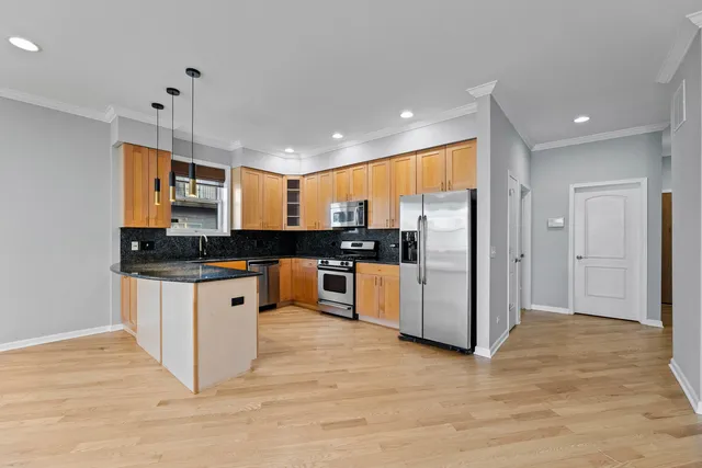 a kitchen with stainless steel appliances granite countertop a refrigerator a sink a stove and a wooden floors