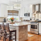a kitchen with stainless steel appliances granite countertop a stove top oven a sink a dining table and chairs