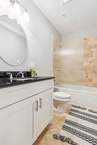 a bathroom with a granite countertop toilet sink and mirror