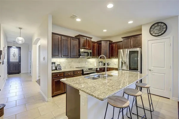 a kitchen with granite countertop a table chairs stove and refrigerator