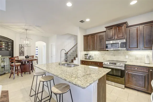a kitchen with stainless steel appliances granite countertop a stove top oven a sink a dining table and chairs